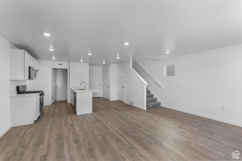Unfurnished living room featuring dark wood-style flooring, recessed lighting, and stairs