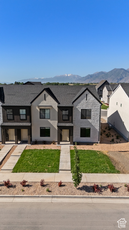 View of front of property featuring a mountain view, a shingled roof, a front yard, and a residential view