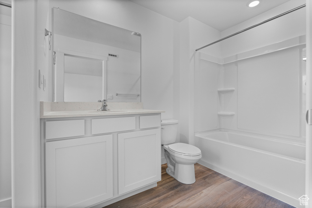 Bathroom with vanity, wood finished floors, shower / bath combination, and recessed lighting
