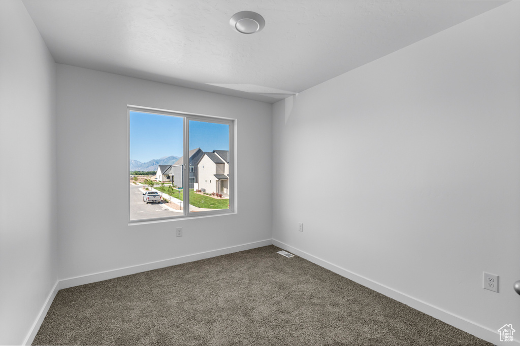 Spare room with dark colored carpet and baseboards