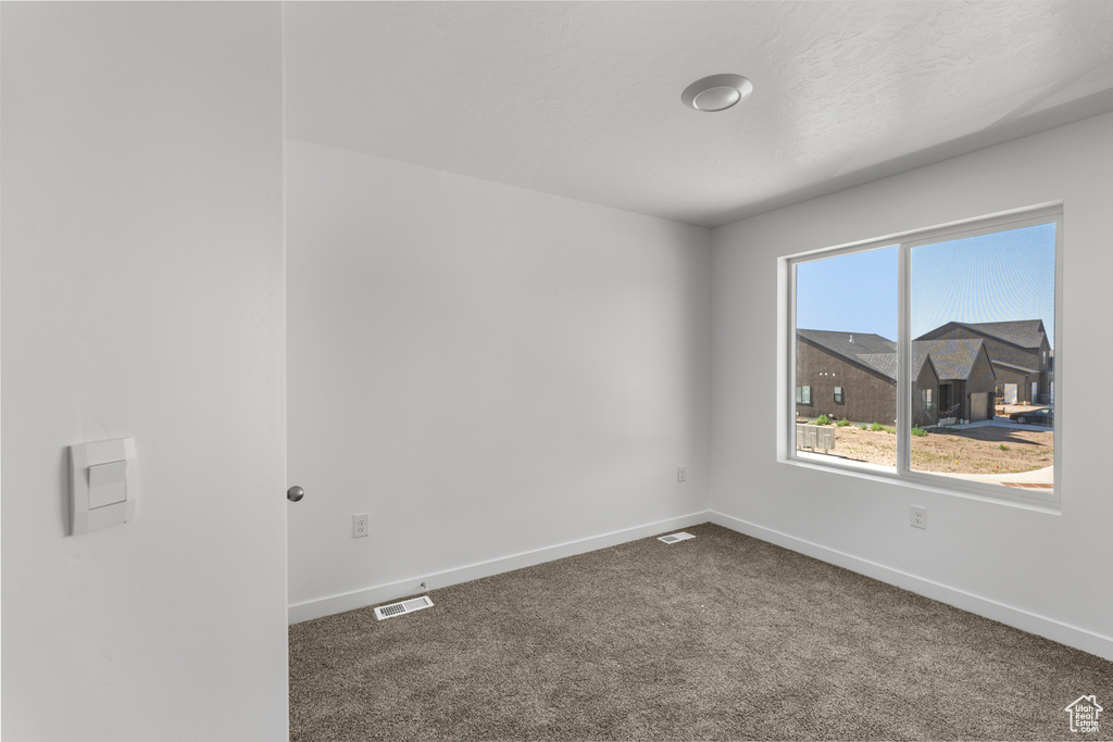 Spare room featuring dark carpet and baseboards
