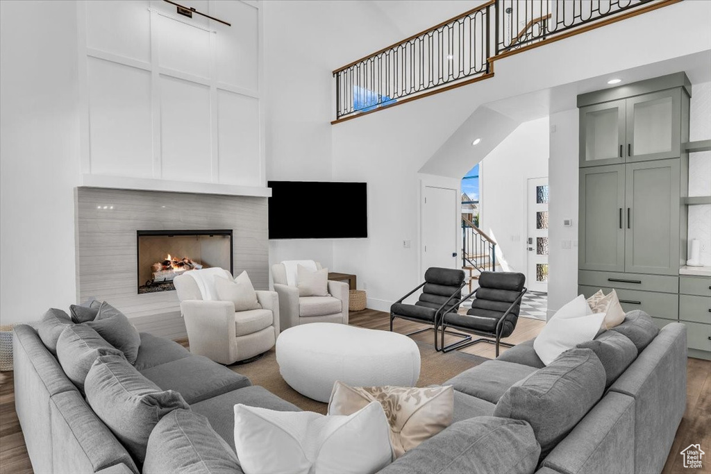 Living area featuring a towering ceiling, wood finished floors, a fireplace, and plenty of natural light