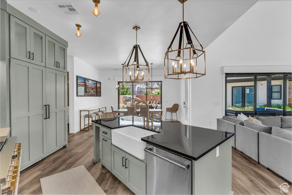 Kitchen featuring stainless steel dishwasher, a chandelier, dark countertops, dark wood-style floors, and open floor plan
