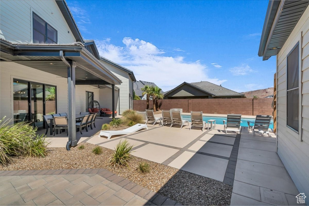 Fenced backyard featuring a ceiling fan, outdoor dining area, and a patio