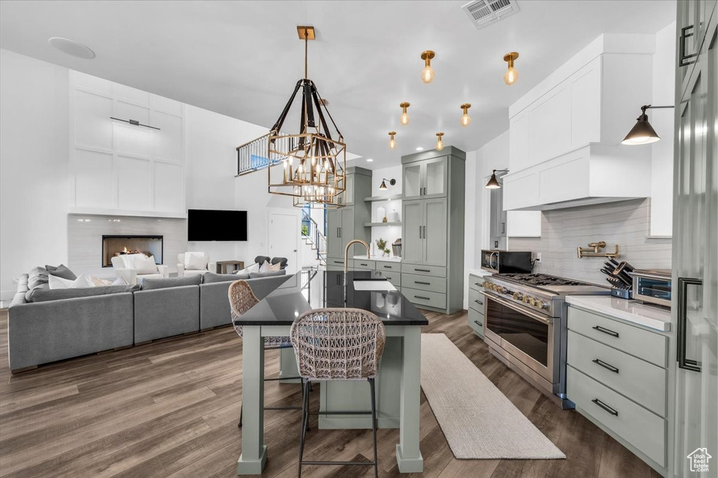 Kitchen with appliances with stainless steel finishes, decorative backsplash, a kitchen breakfast bar, dark wood-style floors, and a center island with sink