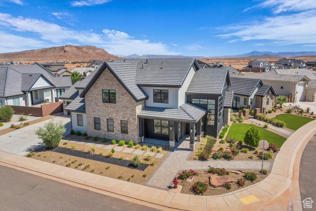 View of front of property featuring stone siding, a mountain view, a residential view, driveway, and a tiled roof
