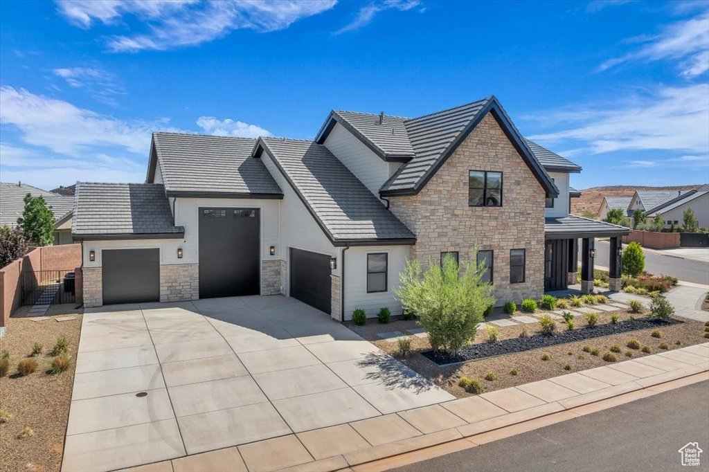 View of front of property with stone siding, an attached garage, and concrete driveway