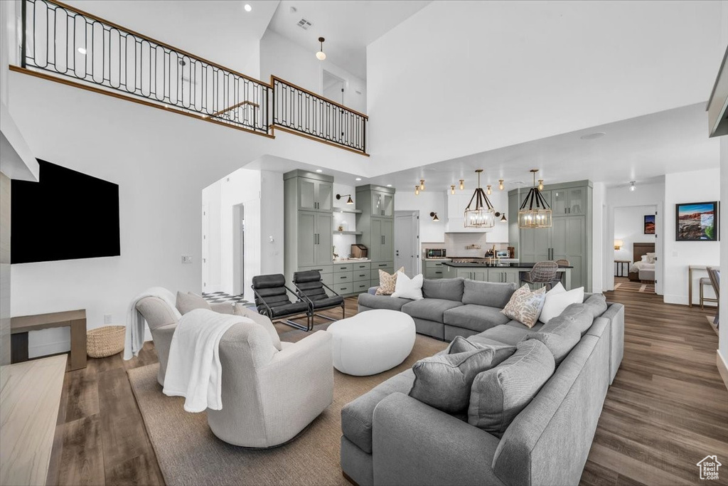 Living area with dark wood finished floors, a chandelier, and a towering ceiling