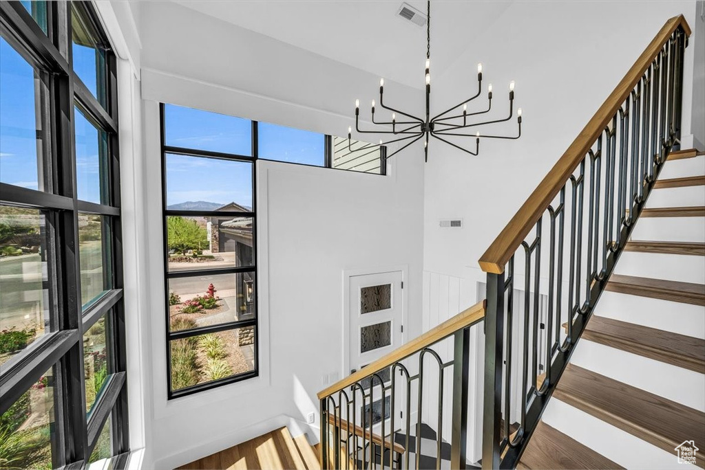 Stairs featuring a chandelier and wood finished floors