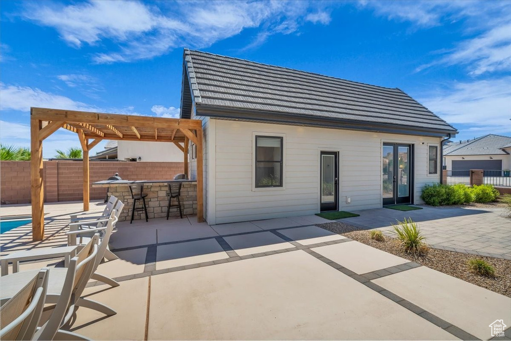 Back of house featuring a pergola, a patio, and a tile roof