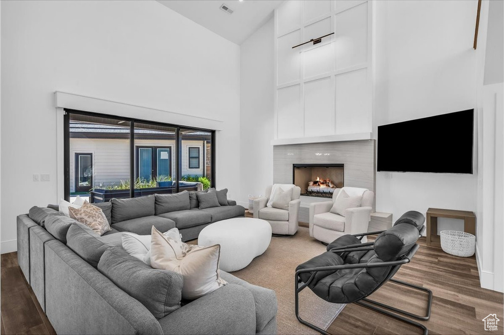 Living room with wood finished floors, high vaulted ceiling, and a high end fireplace
