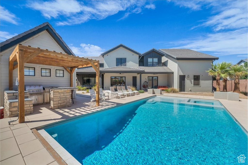 View of pool featuring exterior kitchen, a pergola, a patio, ceiling fan, and a pool with connected hot tub