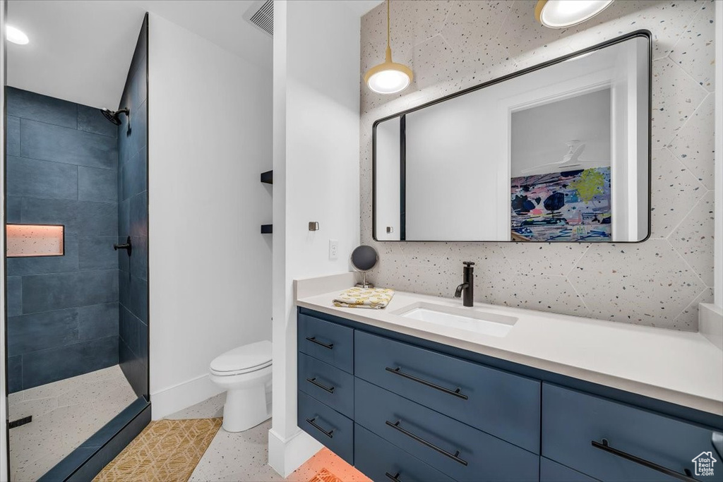 Full bath with tiled shower and vanity