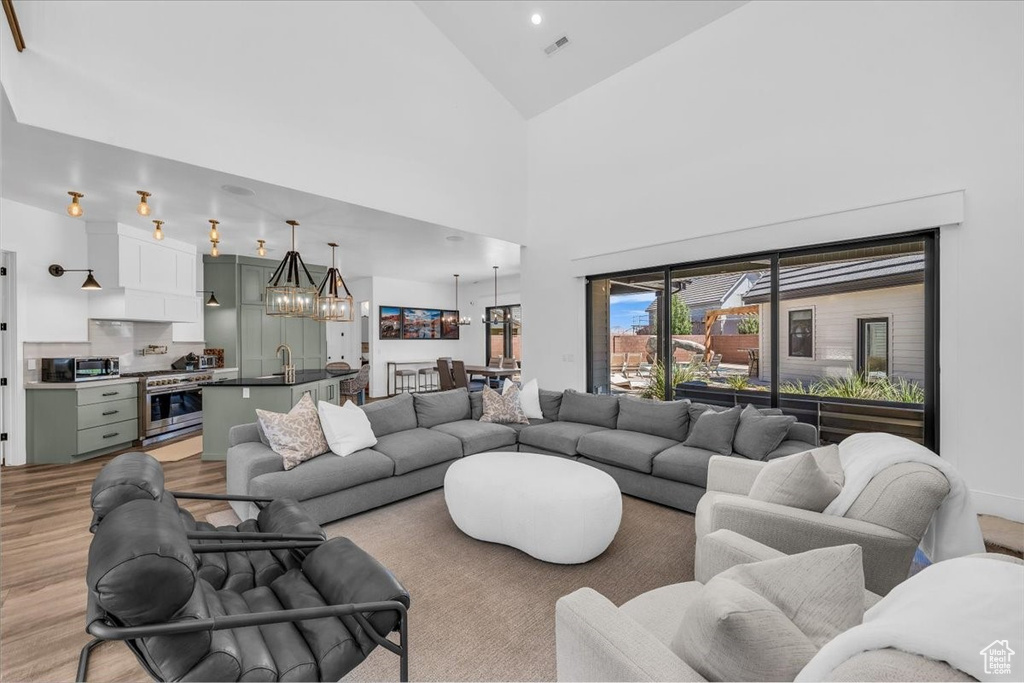 Living room featuring light wood-style floors, a chandelier, and high vaulted ceiling