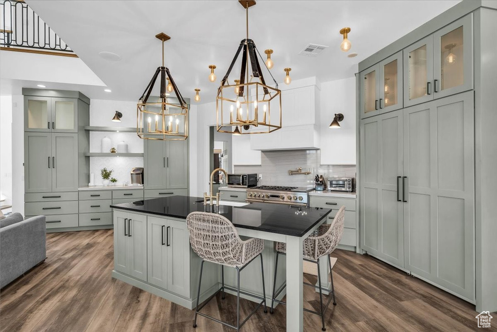 Kitchen with a chandelier, tasteful backsplash, dark wood finished floors, dark countertops, and recessed lighting