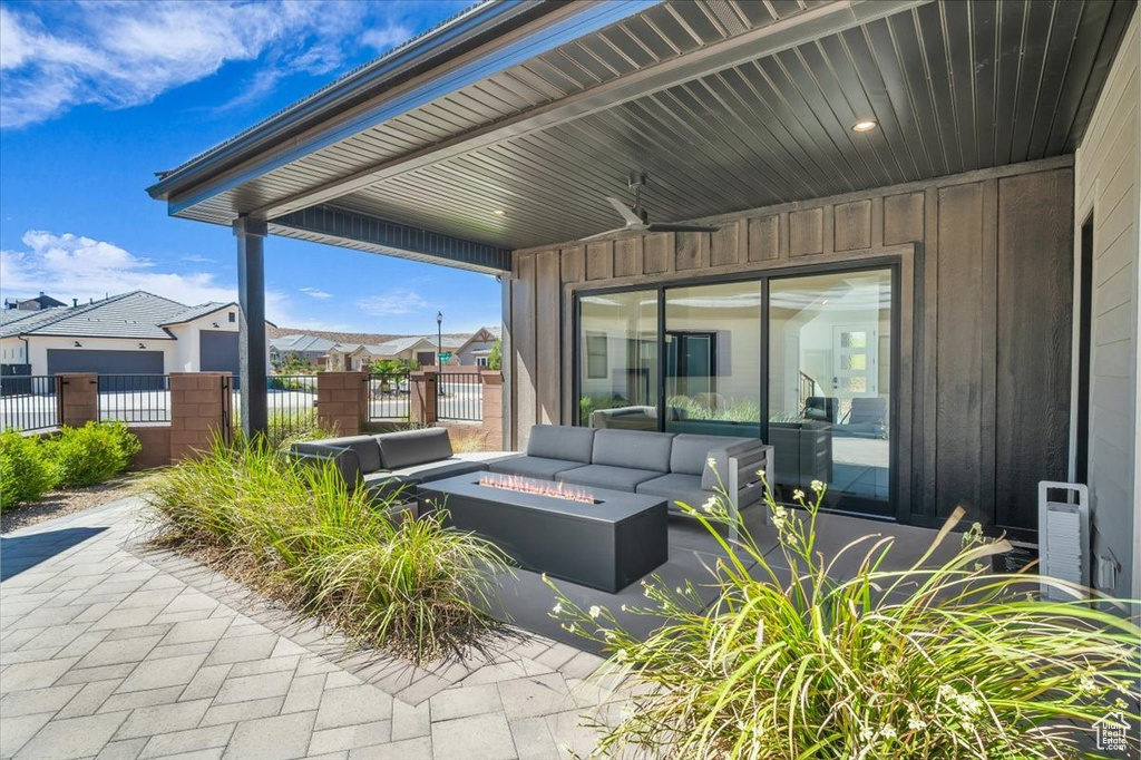 View of patio featuring an outdoor living space with a fire pit, a residential view, and a ceiling fan