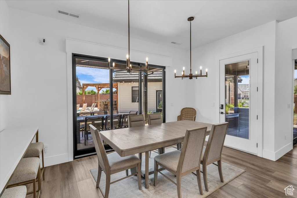 Dining room with a chandelier, healthy amount of natural light, and wood finished floors