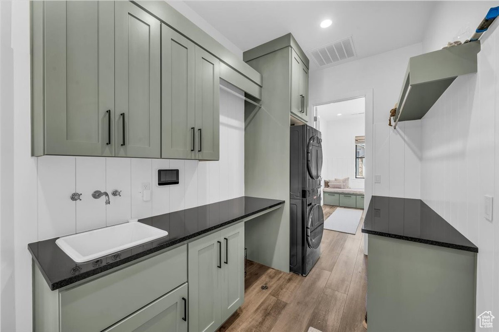 Washroom with cabinet space, stacked washer / drying machine, light wood-style floors, and recessed lighting