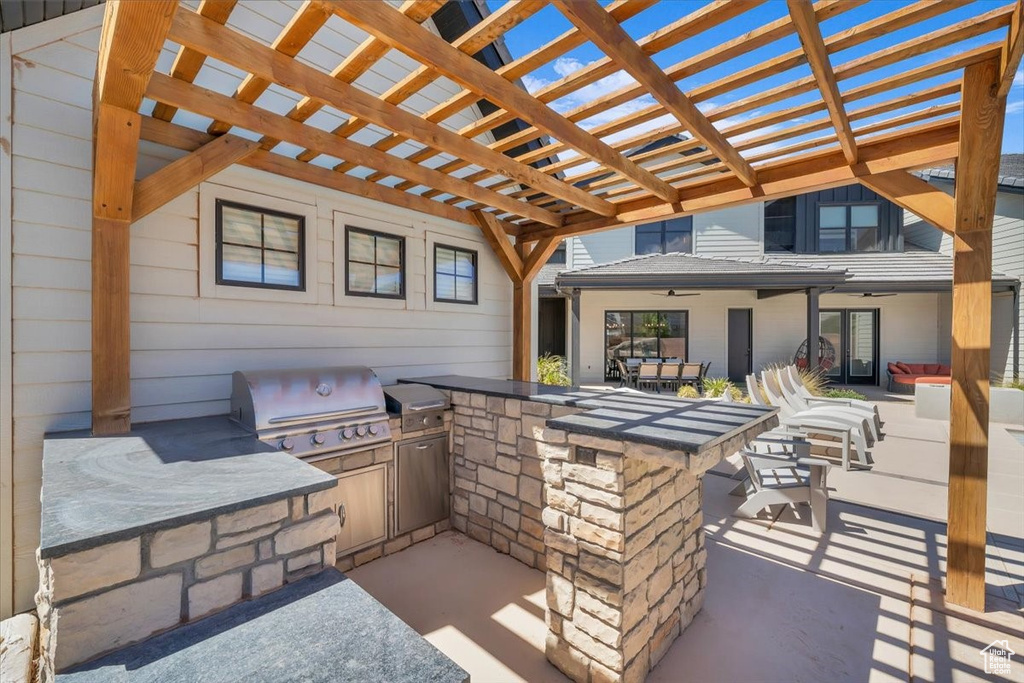 View of patio featuring an outdoor kitchen, a ceiling fan, and a pergola