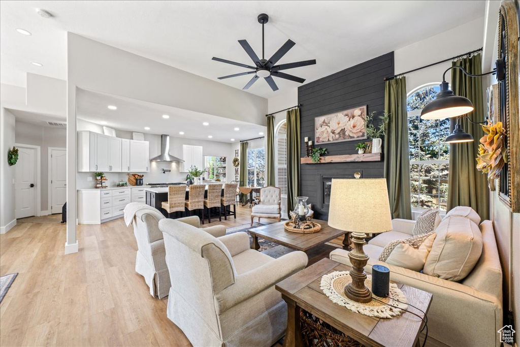 Living area featuring light wood-style flooring, ceiling fan, a fireplace, and recessed lighting