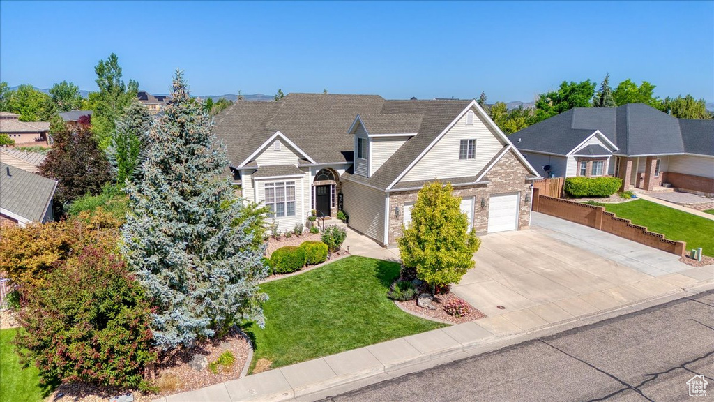 View of front facade featuring concrete driveway, a front lawn, and brick siding