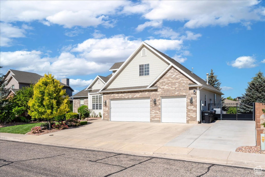 Traditional home with a gate, concrete driveway, brick siding, and a garage