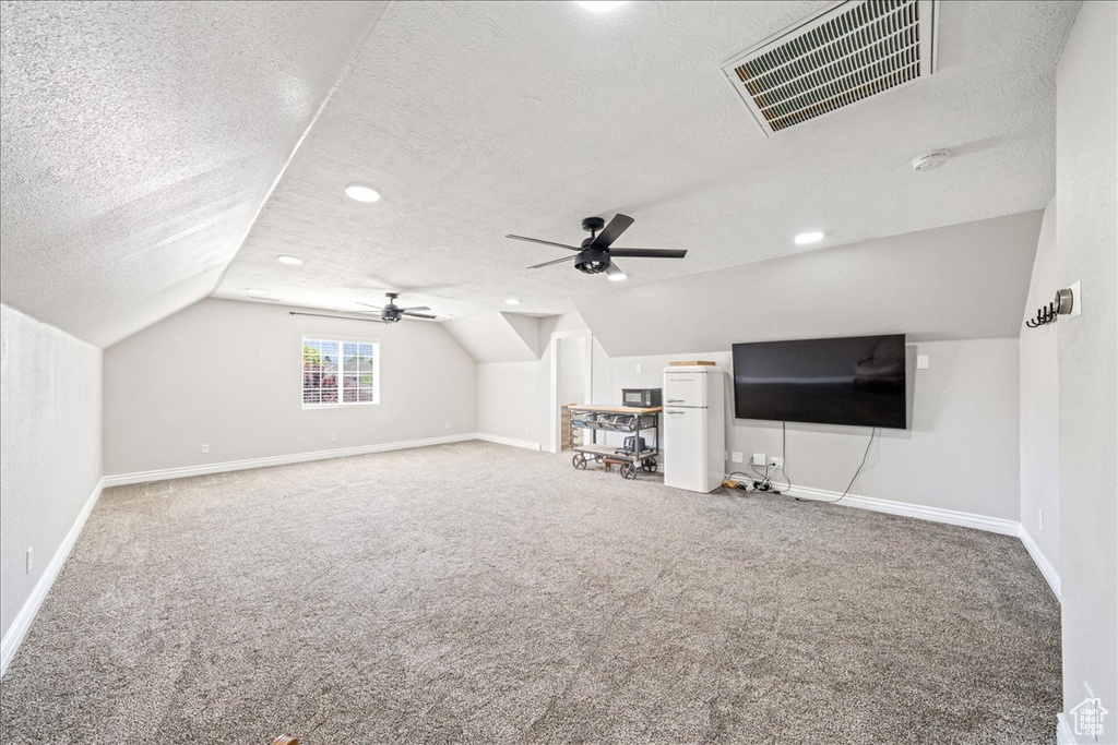 Additional living space with vaulted ceiling, carpet, a textured ceiling, a ceiling fan, and recessed lighting