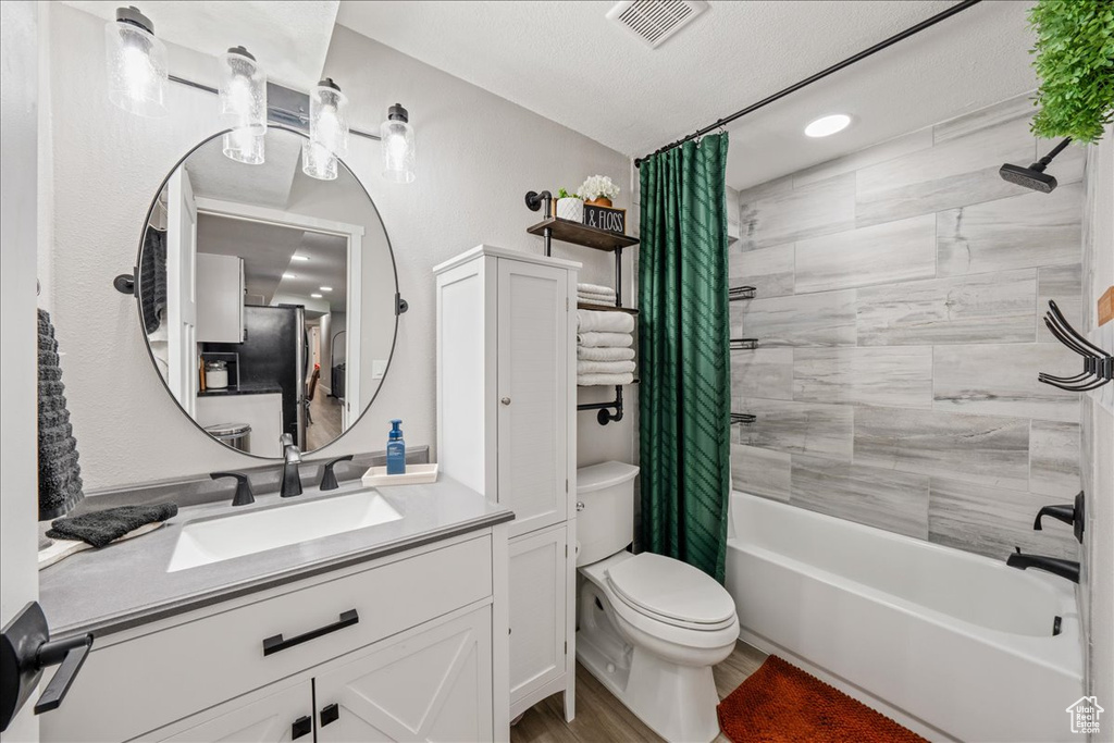 Bathroom with shower / bathtub combination with curtain, vanity, and wood finished floors