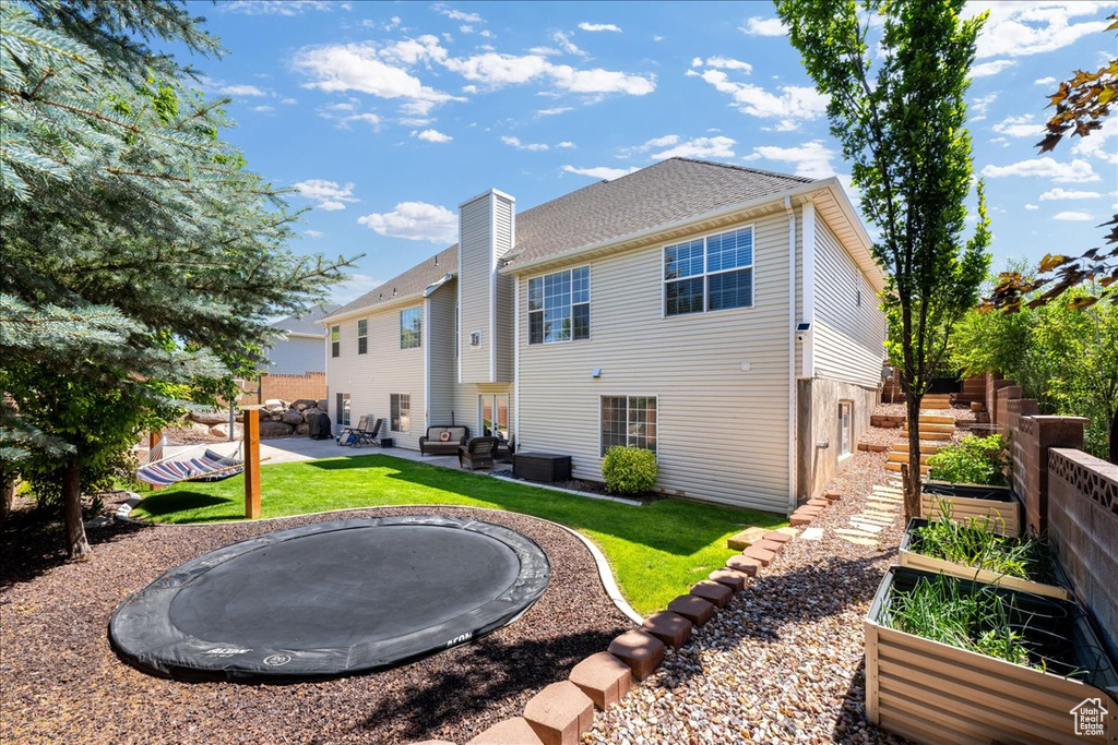Back of property featuring a lawn, a patio area, and a vegetable garden