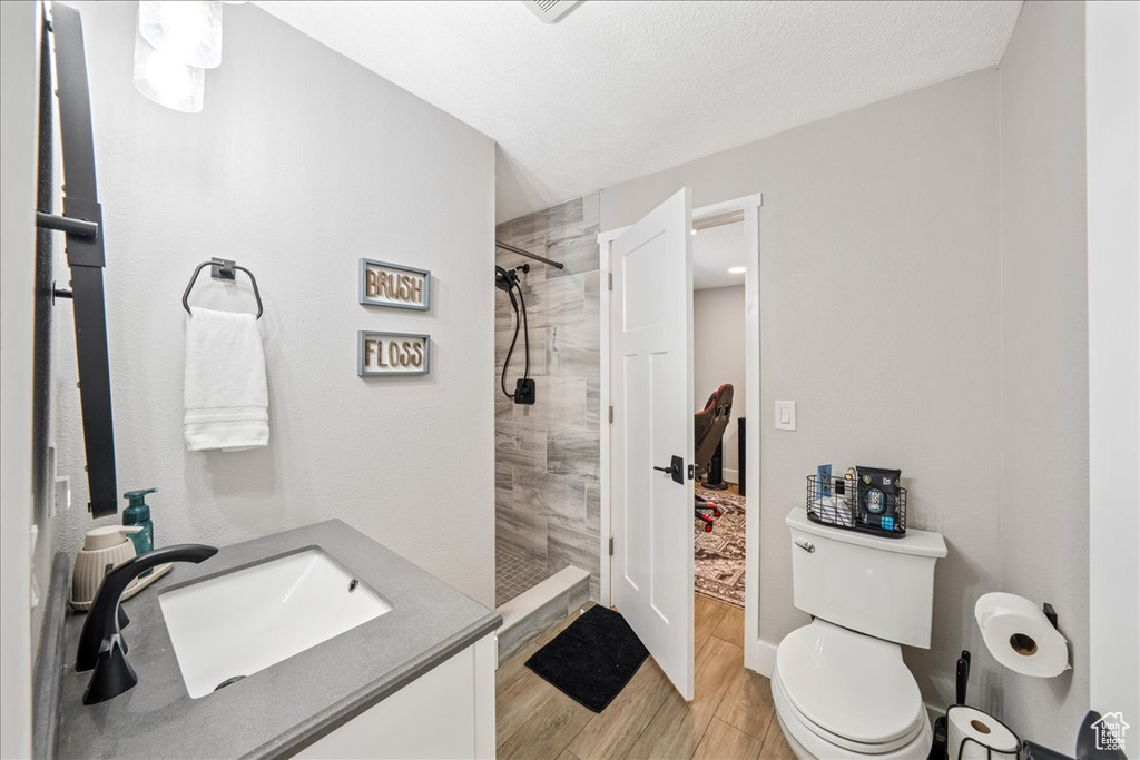 Bathroom with a tile shower, wood finished floors, and vanity