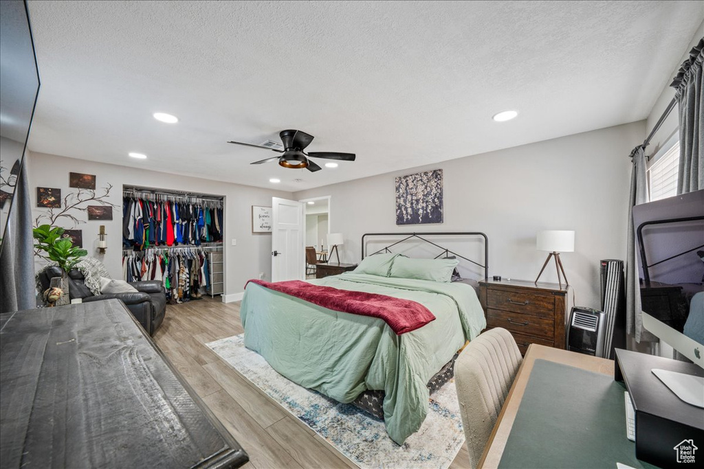 Bedroom featuring wood finished floors, recessed lighting, a closet, ceiling fan, and a textured ceiling