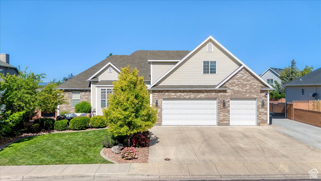 Traditional-style house featuring a garage, concrete driveway, and brick siding
