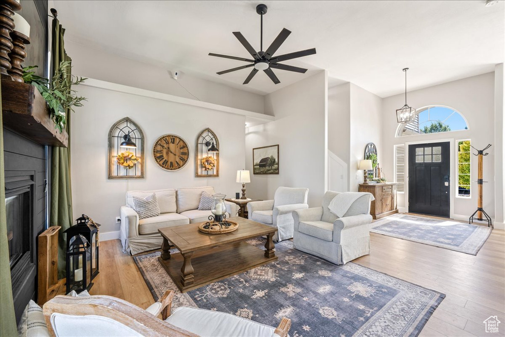 Living area with wood finished floors, ceiling fan, a glass covered fireplace, and a chandelier