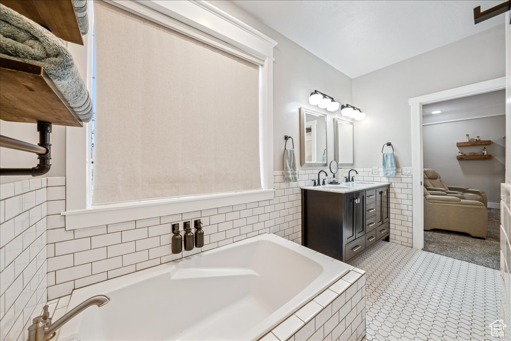 Full bathroom featuring tile walls, vanity, a garden tub, wainscoting, and tile patterned flooring