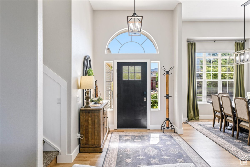 Entryway featuring a chandelier, wood finished floors, and a towering ceiling