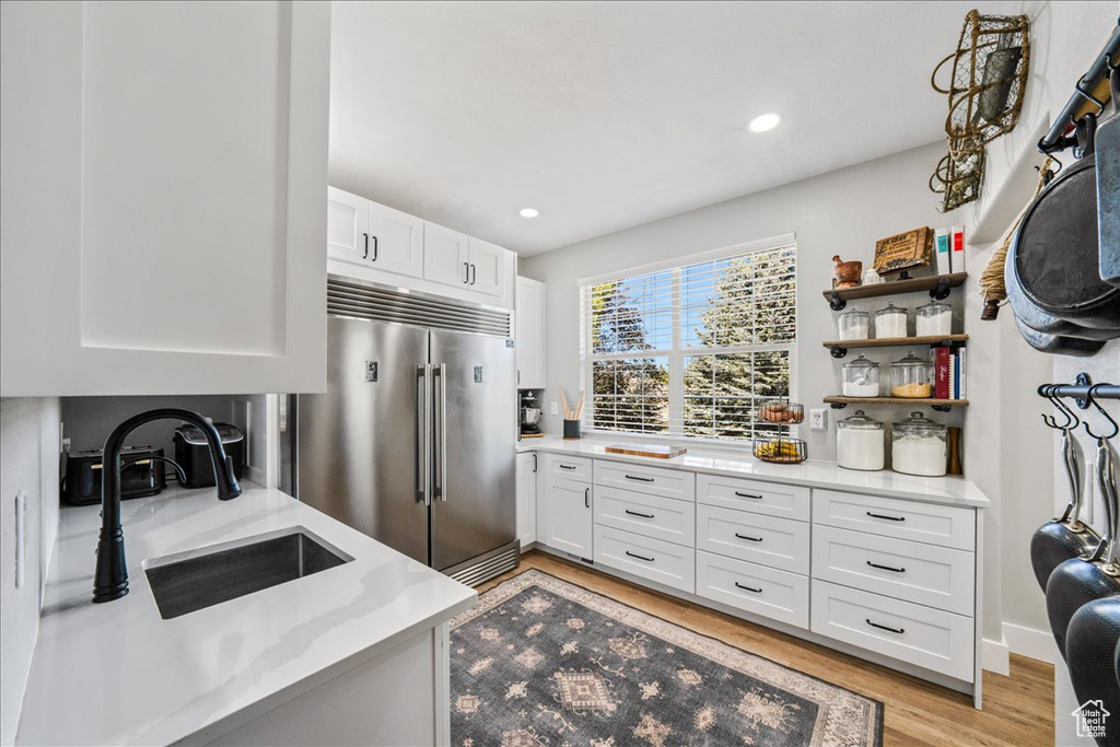 Kitchen featuring stainless steel built in refrigerator, white cabinetry, light wood-style flooring, recessed lighting, and open shelves