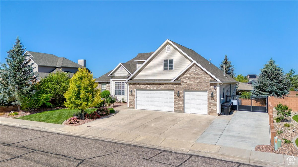 Traditional home featuring driveway, a garage, a gate, and brick siding