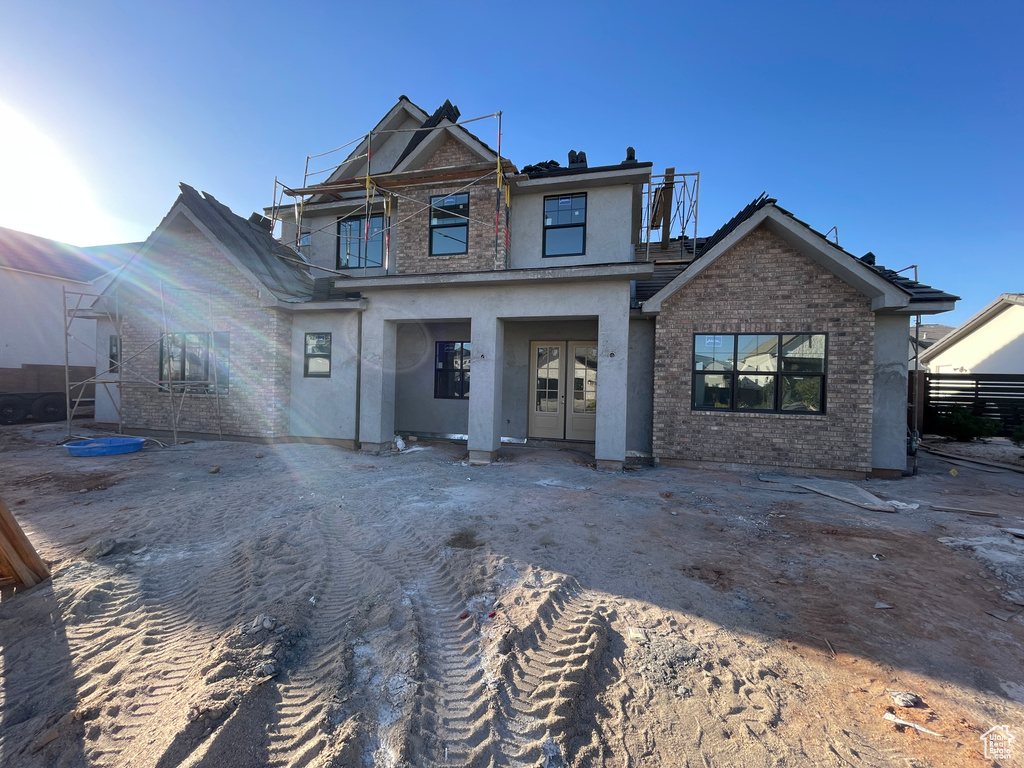 View of front of property featuring stucco siding, french doors, and brick siding