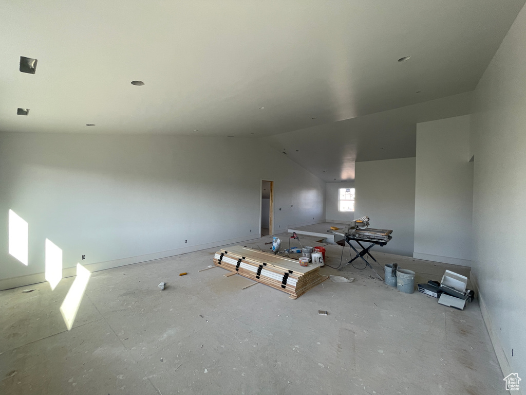 Empty room featuring vaulted ceiling and baseboards