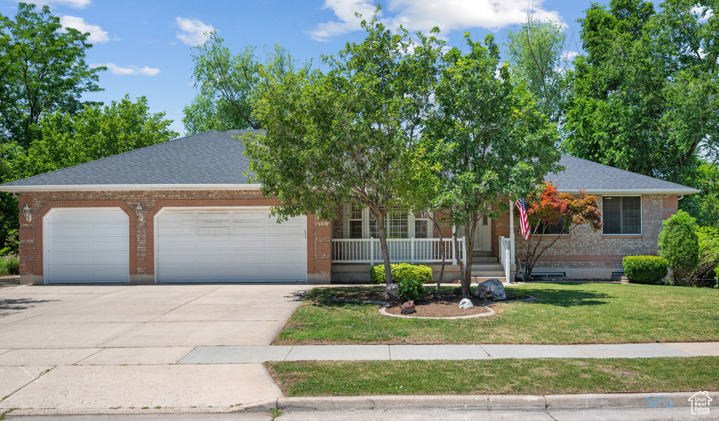 View of front of house with a garage, concrete driveway, brick siding, roof with shingles, and a front yard