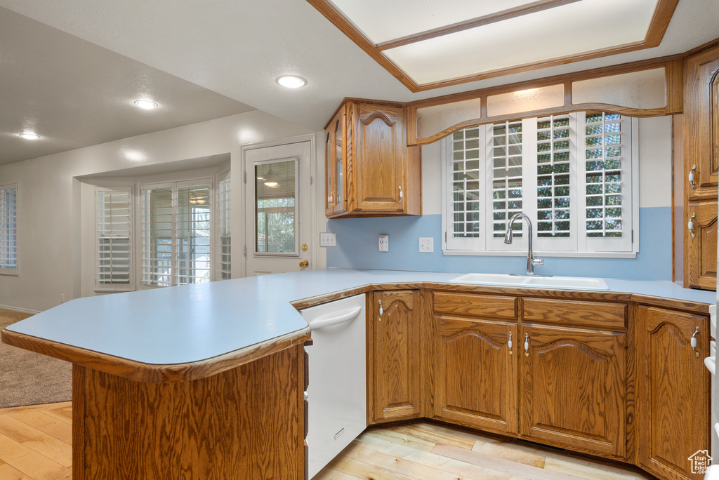 Kitchen featuring white dishwasher, a peninsula, light countertops, light wood finished floors, and recessed lighting