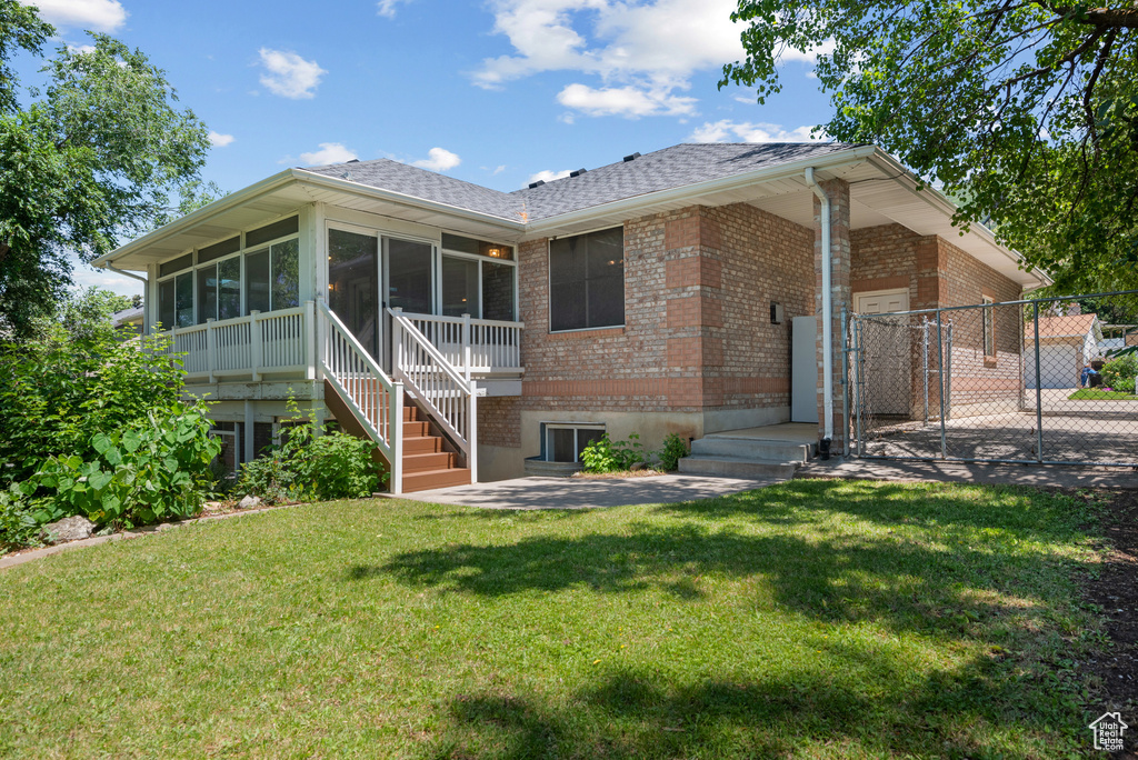 View of front of property featuring a sunroom, brick siding, a shingled roof, a gate, and stairs