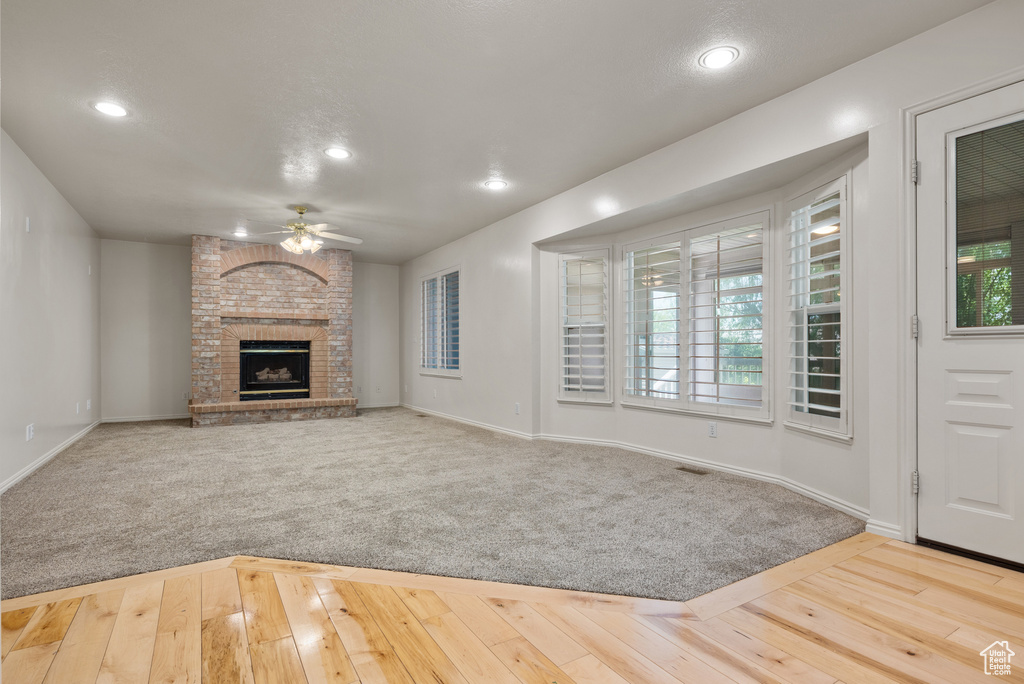 Unfurnished living room featuring a ceiling fan, recessed lighting, healthy amount of natural light, a fireplace, and hardwood / wood-style flooring