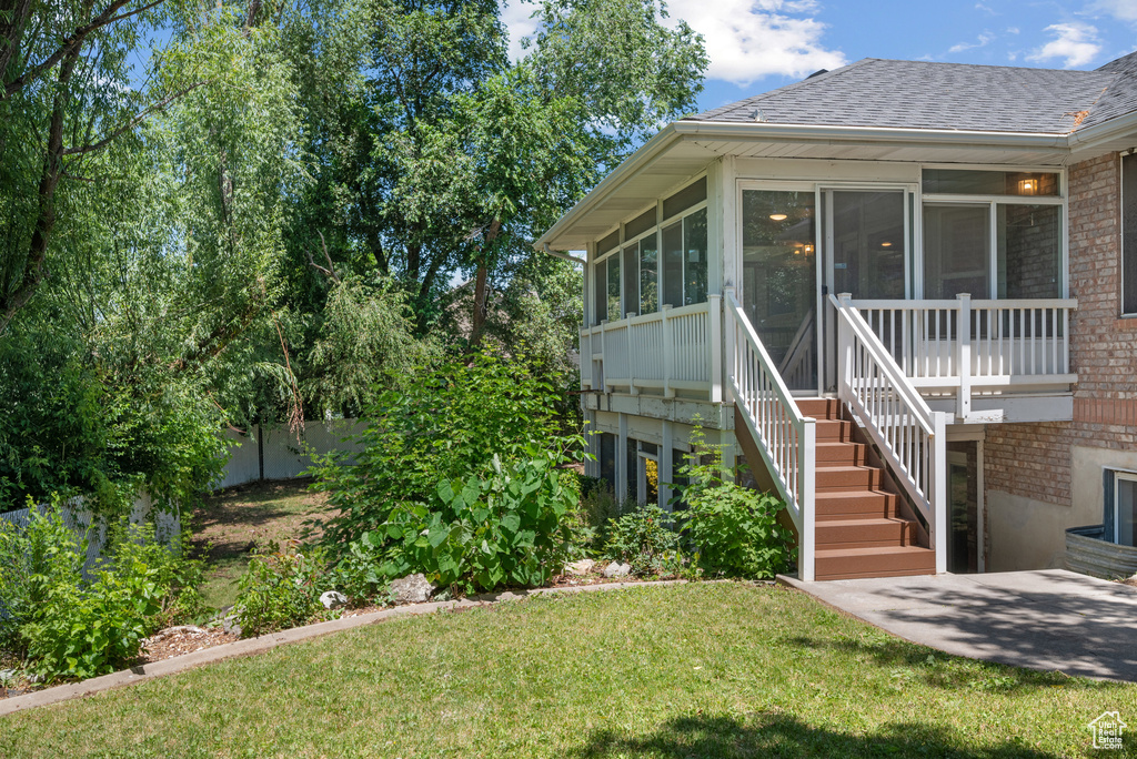 View of green lawn featuring stairs and a sunroom