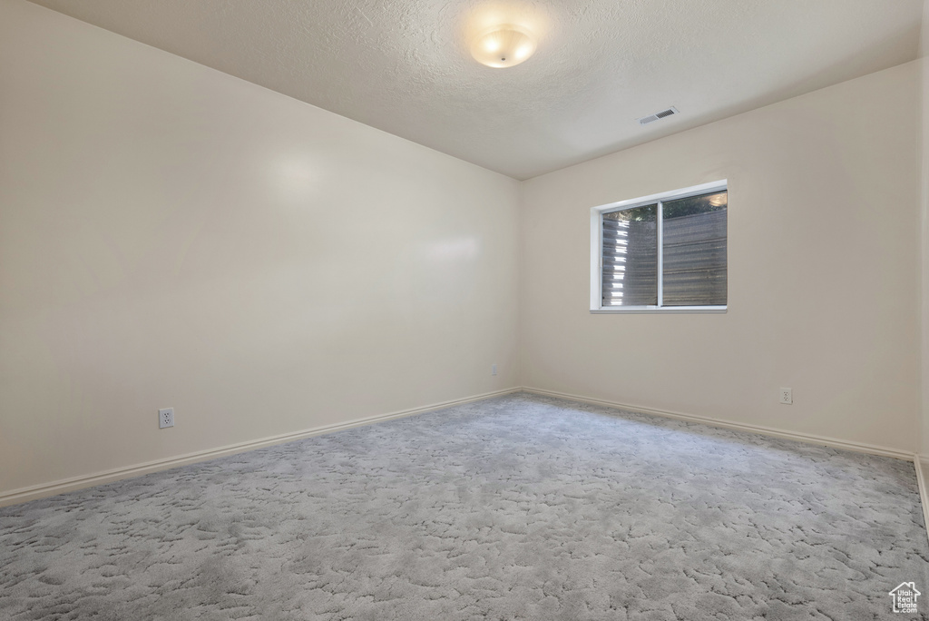 Carpeted spare room with baseboards and a textured ceiling