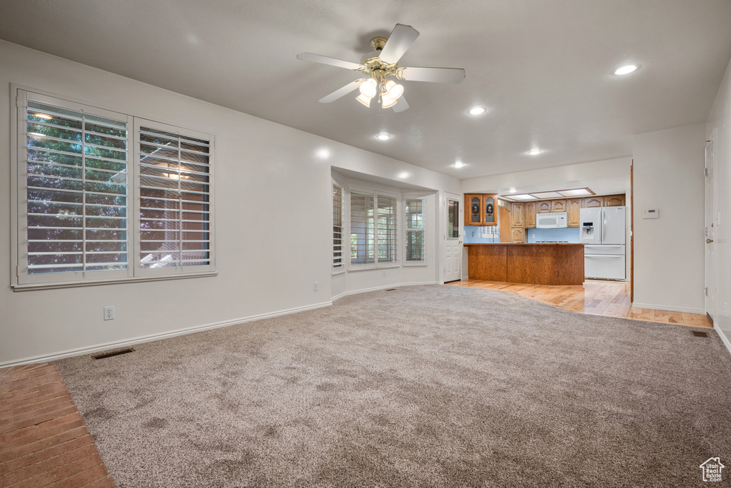 Unfurnished living room featuring light colored carpet, a ceiling fan, and recessed lighting
