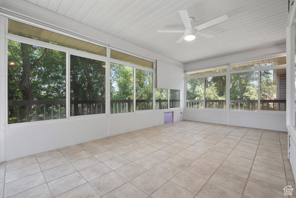 Unfurnished sunroom with ceiling fan and tile patterned flooring
