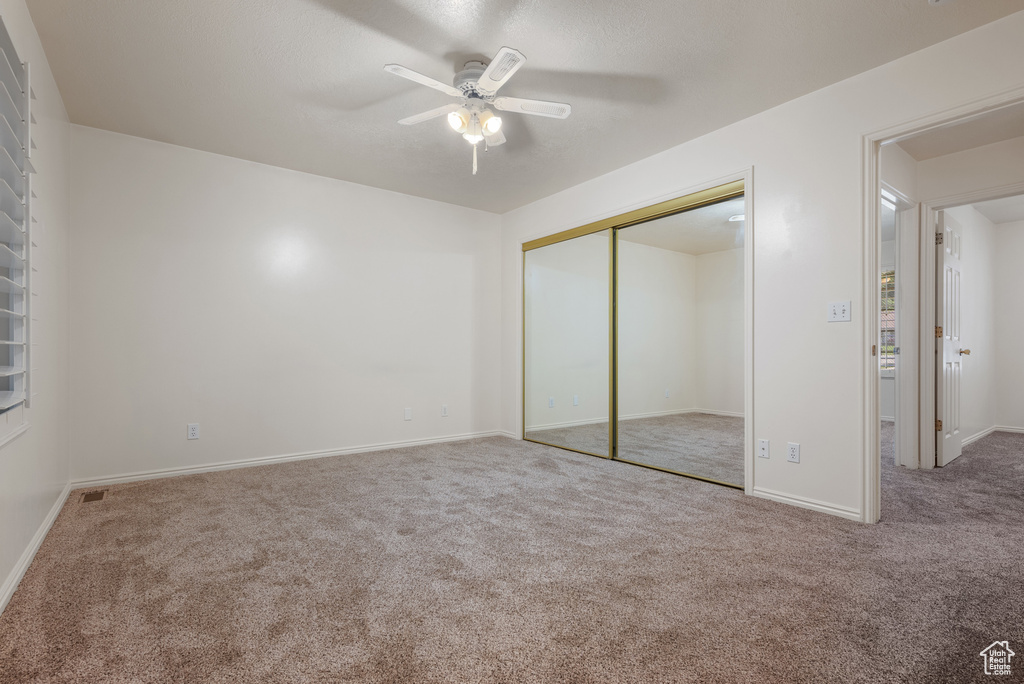 Unfurnished bedroom with carpet floors, a closet, and ceiling fan