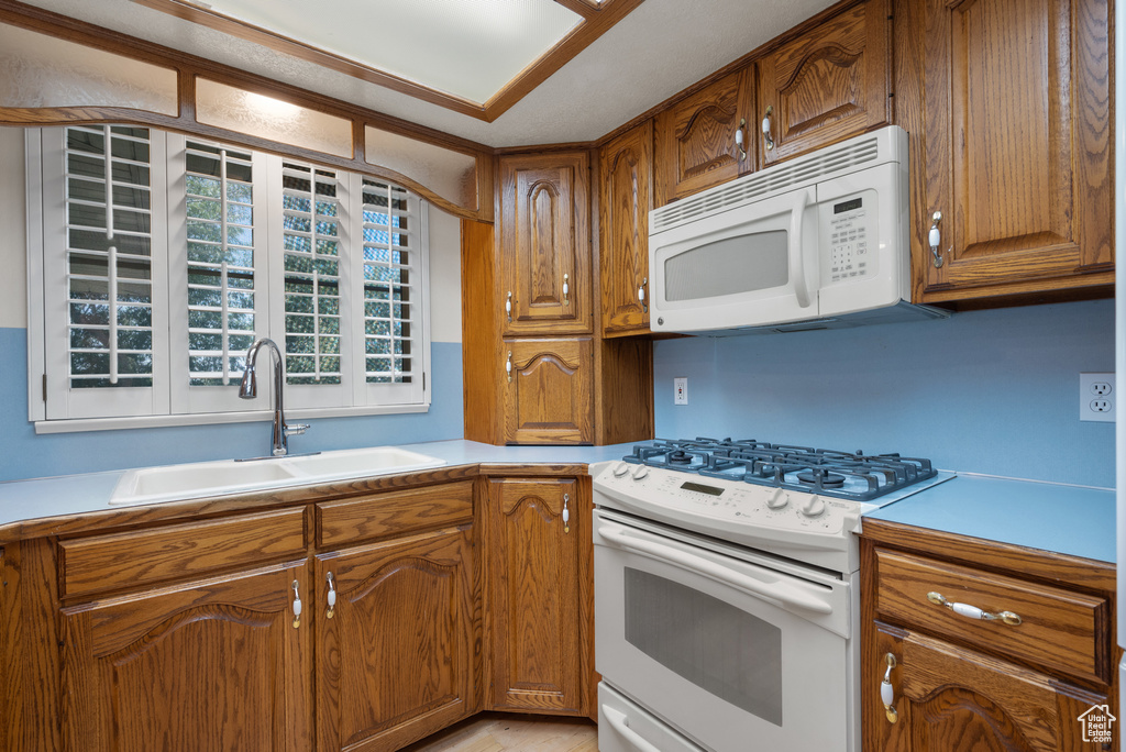 Kitchen with white appliances, light countertops, and brown cabinetry
