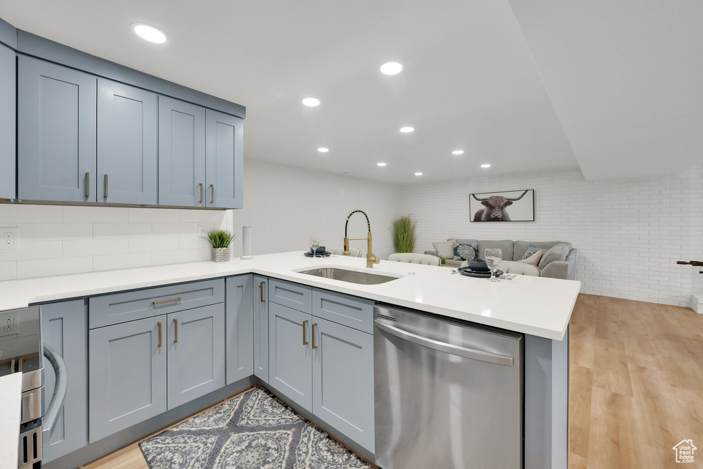 Kitchen featuring dishwasher, a peninsula, light wood finished floors, open floor plan, and recessed lighting